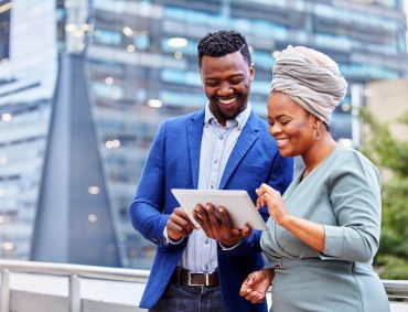Shot of two colleagues using a digital tablet together against a city background